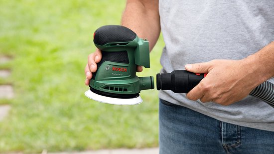Groene Bosch excenterschuurmachine wordt aangesloten op stofzuigerslang.