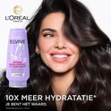 Mannequin aux cheveux brillants, à côté d'une bouteille d'après-shampooing L'Oréal Elvive Hydra Hyaluronic.