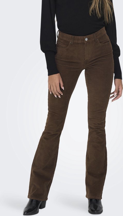 Vrouw in zwarte coltrui en bruine corduroy flare broek, staand.