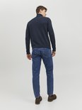 Man met de rug naar de camera, draagt donkerblauwe coltrui en jeans