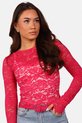 Haut en dentelle fuchsia à motif floral, porté par une femme aux cheveux bruns et un jean clair.