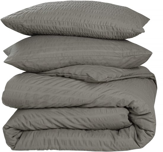 Coussins gris empilés et housse de couette avec un motif subtilement côtelé.
