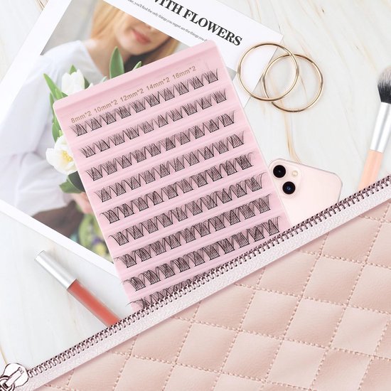 Roze doosje met wimpers in een make-uptasje naast een lippenstift en gouden ringen.