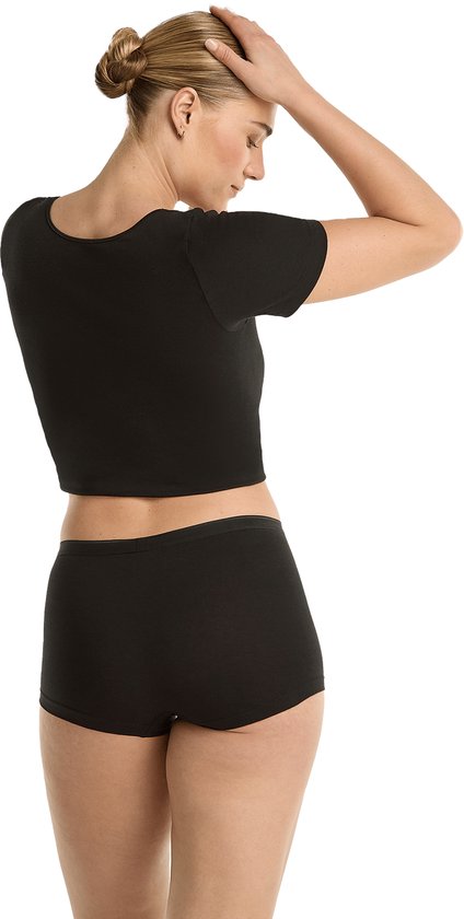 Model van achteren gezien, met zwarte crop top en zwarte shorts.