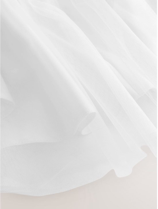 Gedetailleerd beeld van de witte tule rok van een jurk met lagen.