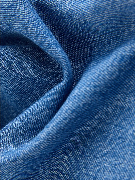 Close-up van blauw denim met de typische textuur en kleurverschillen.