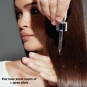 Close-up van een vrouw met lang, donkerbruin haar, waarbij een druppelaar product aanbrengt om vocht af te stoten.