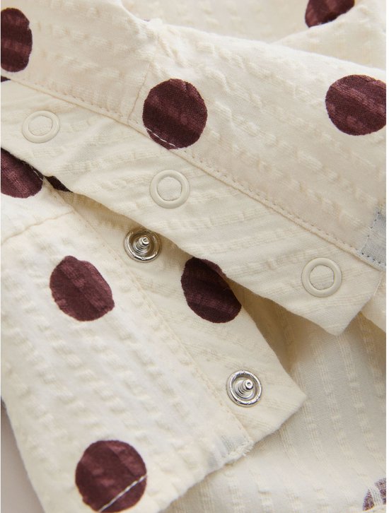 Sluiting met drukknoopjes op de crèmekleurige playsuit met bruine stippen.