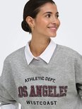 Model met grijze sweater met "LOS ANGELES WESTCOAST" print.