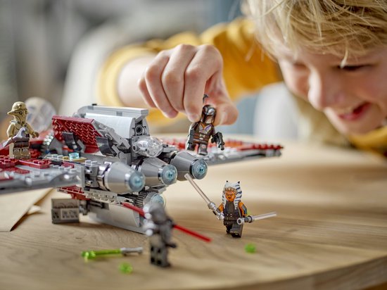 Close-up van een jongen die speelt met de LEGO Star Wars T-6 Jedi Shuttle en minifiguren. De shuttle heeft rode en grijze vleugels.