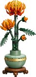 Chrysanthème Lego dans un vase vert avec une bande dorée et un socle marron. Les fleurs sont orange et rouges.