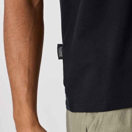 Detail van een zwart t-shirt met een geweven label met tekst.