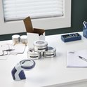 DYMO Omega labelmaker op een bureau met potten, etiketten en een notitieboekje.