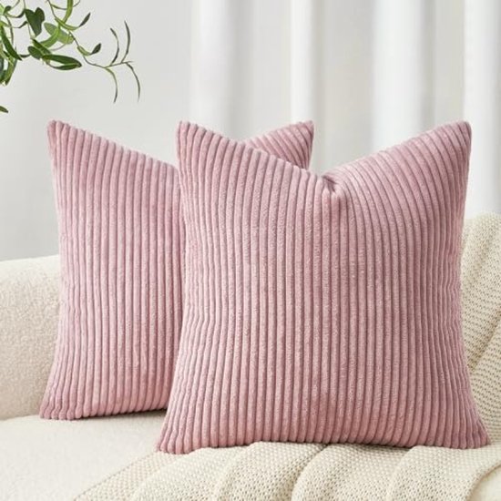 Deux coussins rose en velours côtelé avec côtes verticales sur un canapé.