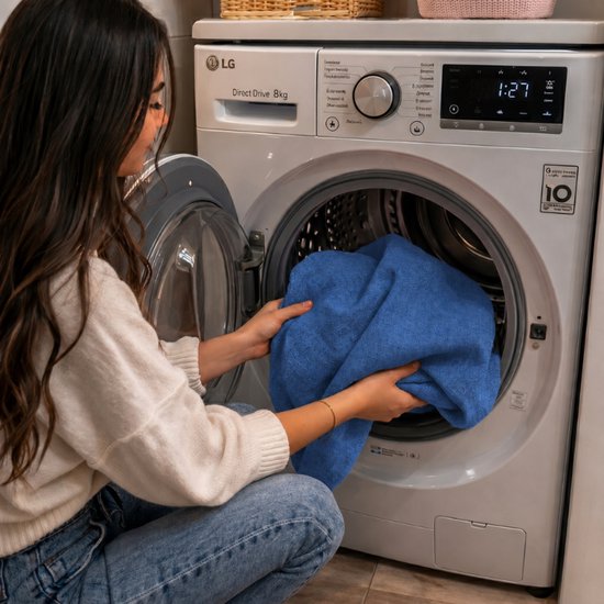 Vrouw doet blauw, geweven wasgoed in een LG wasmachine.