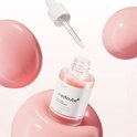 Medicube PDRN Pink Peptide Serum flesje met druppelaar. Flesje zweeft en is omringd door roze bubbels.