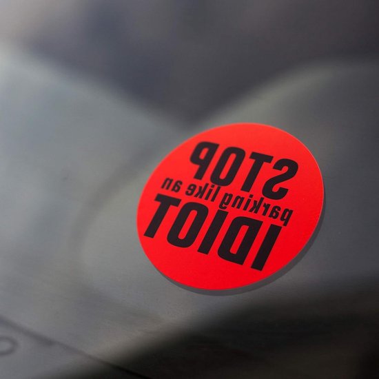 Autocollant rond rouge avec texte noir 'STOP IDIOT'.