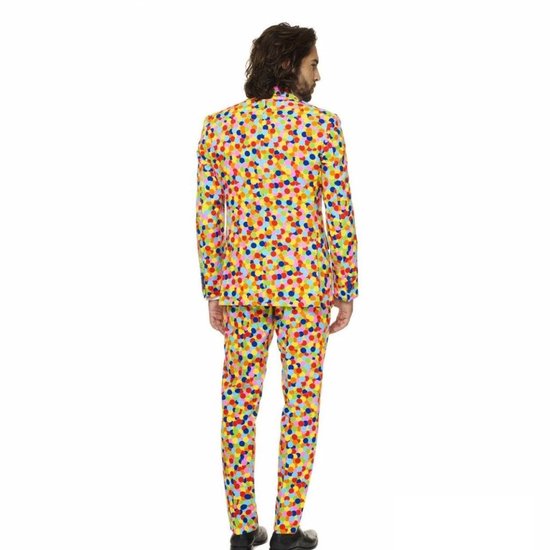Man in een veelkleurig pak met confettiprint en wit shirt, achter-aanzicht.