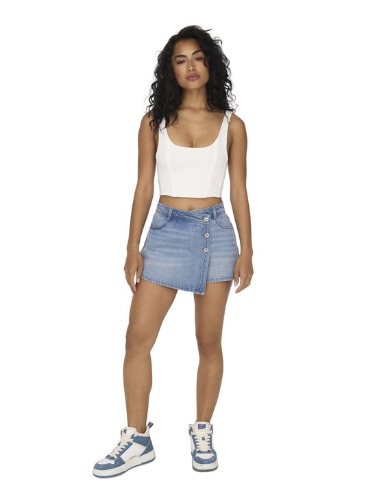Model draagt een lichtblauwe denim skort met gekruiste overslag en knoopsluiting aan de voorzijde.