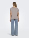 Model van achteren gezien in een lichtbruine top met omgeslagen mouwen en wijde jeans.
