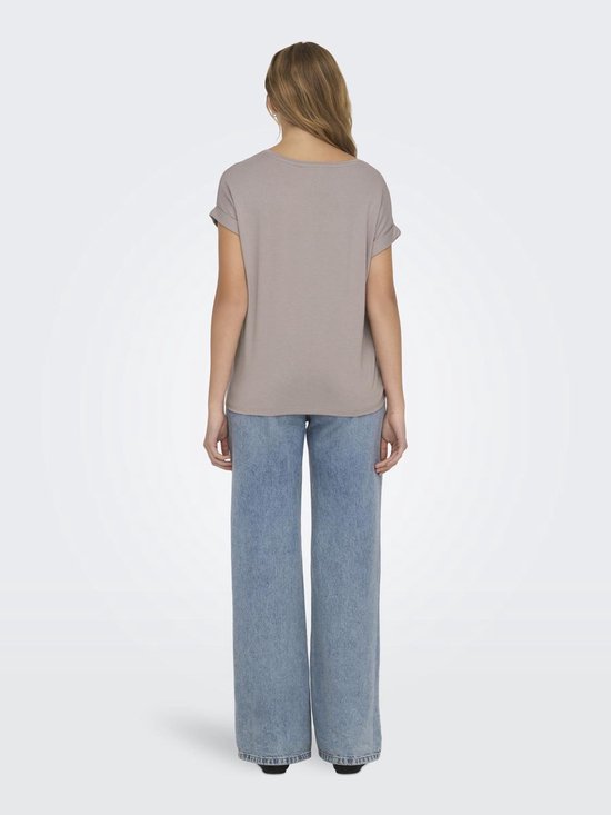 Model van achteren gezien in een lichtbruine top met omgeslagen mouwen en wijde jeans.