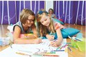Twee meisjes liggen op de grond en kleuren met STABILO Trio A-Z stiften. Een derde meisje kijkt toe.
