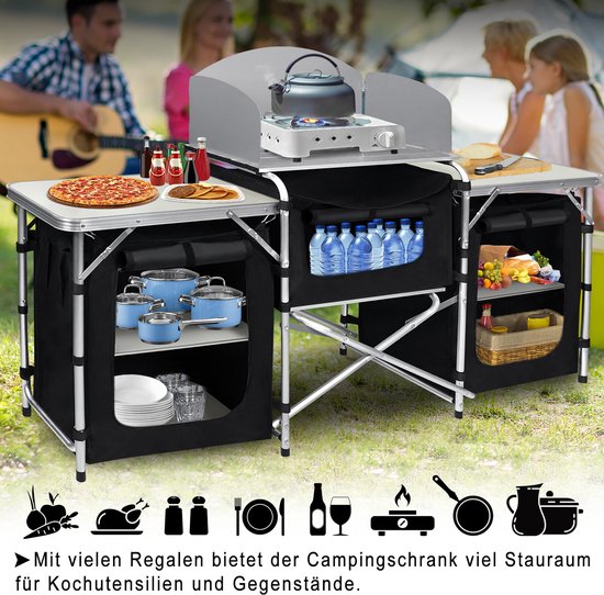 Campingkeuken met aanrechtbladen, gasbrander, waterkoker, pizza, geroosterde kip, fruit, groenten en kookgerei.