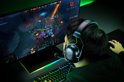 Persoon met zwarte Razer gaming headset, spelend op een computer met het spel Dota 2.