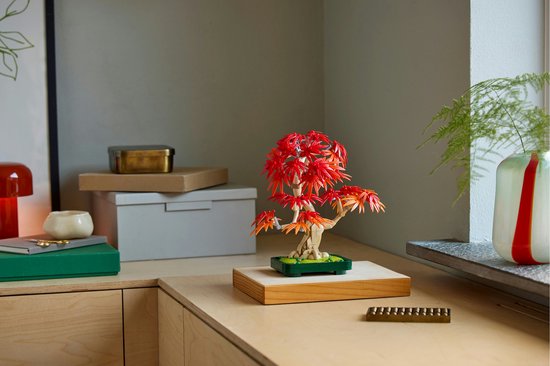 LEGO Japanse esdoorn boompje met rode en oranje bladeren op een bureau.