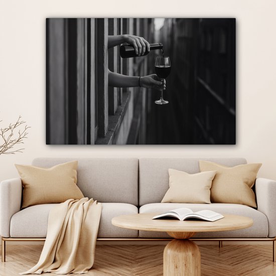 Zwart-wit canvas van handen die wijn schenken boven een moderne bank in een licht interieur.