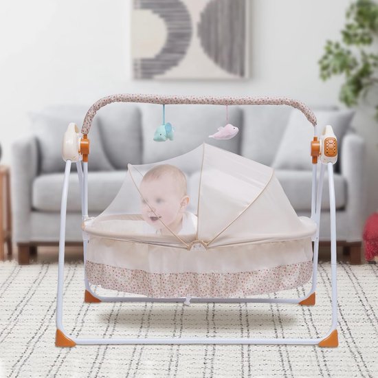 Een baby zit rechtop in een schommelwieg met klamboe. De wieg staat op een vloerkleed in een woonkamer.