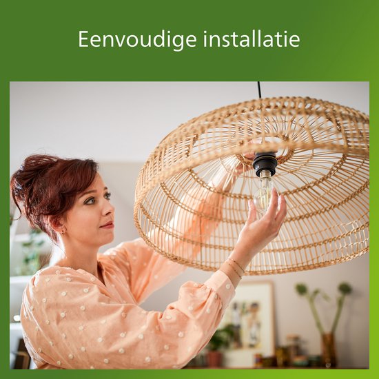 Een vrouw installeert een lamp in een rotan lampenkap.