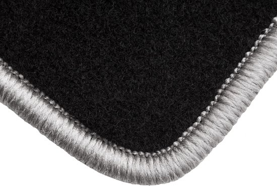 Tapis noir avec passepoil gris, gros plan sur le coin.