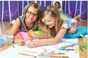 Twee meisjes liggen op de grond en kleuren op een groot vel papier met STABILO Trio A-Z stiften.