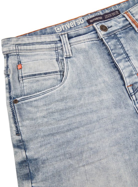 Voorpand van een lichtblauwe korte spijkerbroek met een coin pocket, oranje stiksels en merklabel.