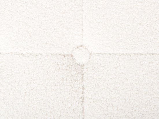 Detailopname van de textuur van de witte bouclé stof van de poef met een knoop.