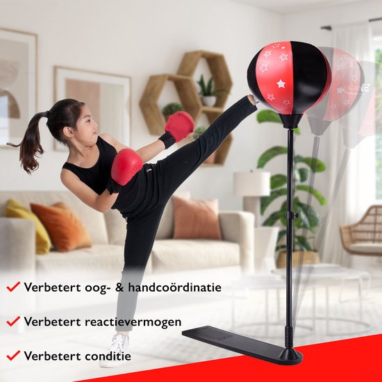 Meisje met rode handschoenen trapt tegen rode/zwarte boksbal. Binnen interieur.