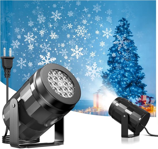 Zwarte LED-projector voor kerst, die sneeuwvlokken op een muur achter een kerstboom projecteert.