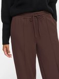 Detail van bruine wijde broek met trekkoord en naden.
