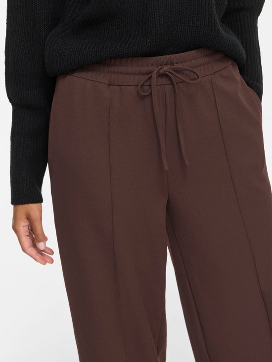 Detail van bruine wijde broek met trekkoord en naden.