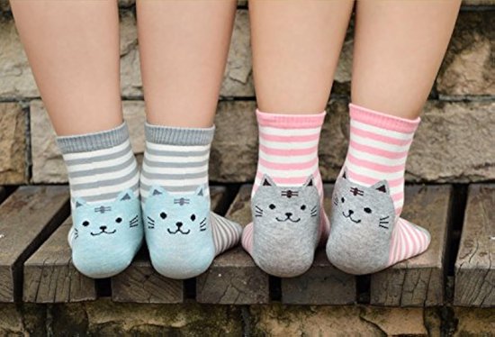 Twee paar sokken met kattengezichtjes en strepen. Eén paar is lichtblauw met grijze strepen, het andere paar is roze met witte strepen.