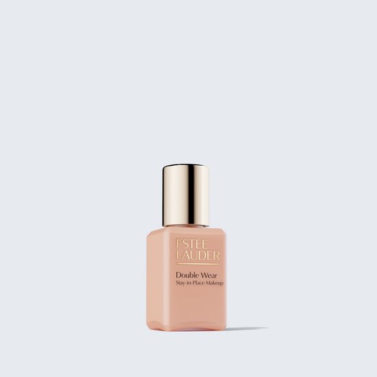 Kleine glazen fles Estée Lauder Double Wear foundation met goudkleurige dop op een lichte achtergrond.
