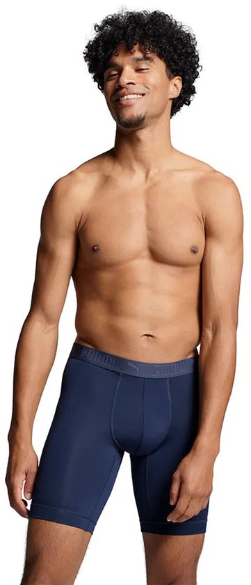 Man met donkere huid en krullend haar, draagt een marineblauwe boxer met grijze tailleband.