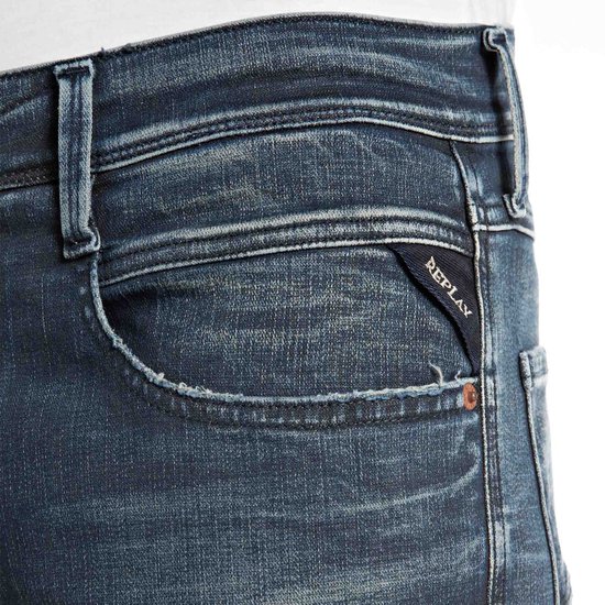 Close-up van het horlogezakje van een donkerblauwe Replay jeans met een zwart Replay label.