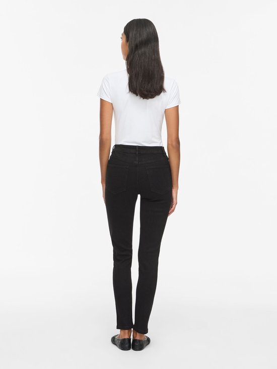 Achterzijde van model in zwarte skinny jeans en wit T-shirt.