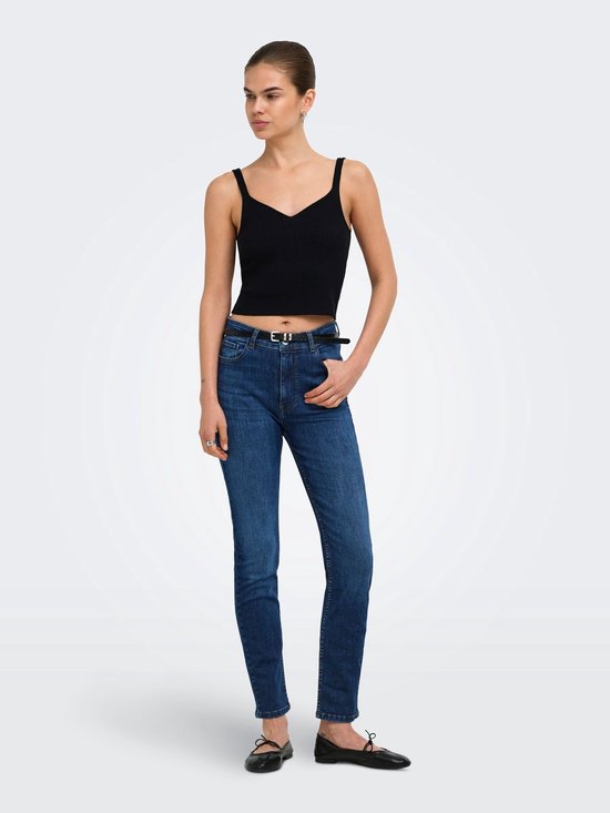 Model draagt een zwarte top en donkerblauwe slim fit jeans met zwarte riem en ballerina's.