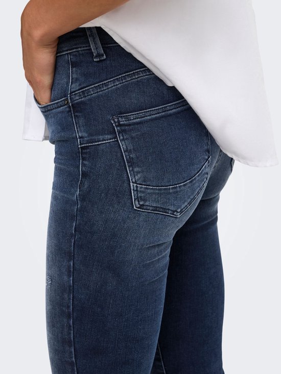Detail van de achterzakken van de blauwe jeans met push-up pasvorm en wit overhemd.