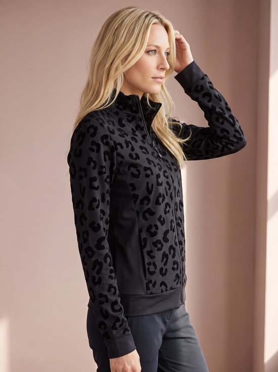 Model met blonde haren draagt een zwarte sportjas met zwarte panterprint op de voorkant en mouwen.