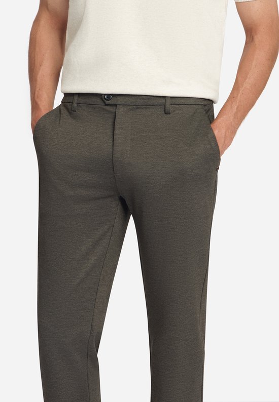 Close-up van een man die een donkerbruine jersey pantalon met steekzakken draagt.