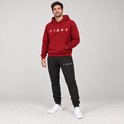 Man met bordeauxrode hoodie met 'VIBES'-opdruk en zwarte joggingbroek met 'VIBES'-opdruk.